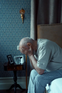An image of an old man holding his face in his hands