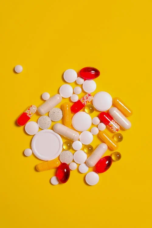 Medicines in tablet, capsule, and gel form on a yellow background