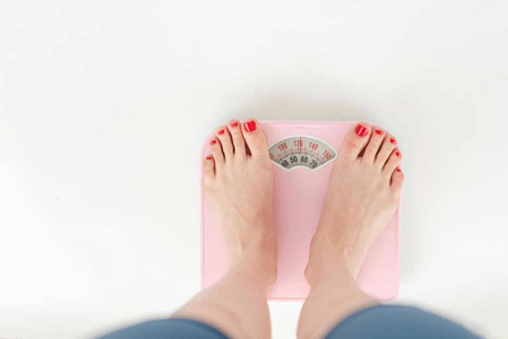 Woman checking her weight on a scale during a holistic weight loss program